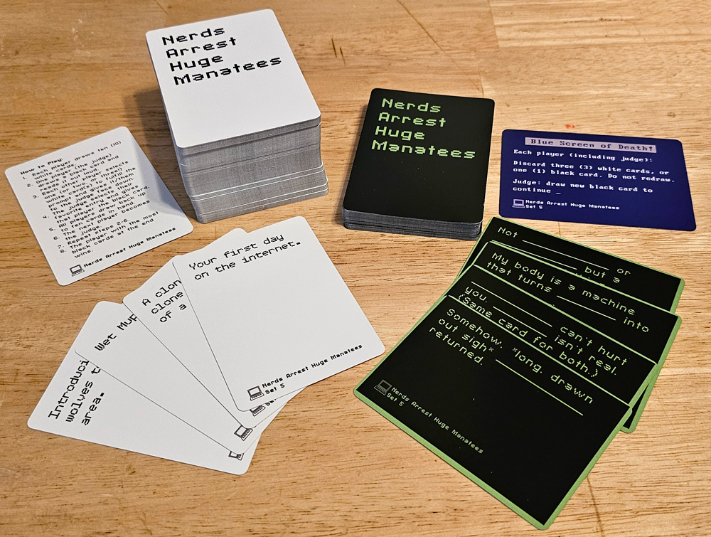 Stacks and spreads of white and black cards. The backs read "Nerds Arrest Huge Manatees." The fronts say things like "Your first day on the internet." and "Somehow, *long, drawn out sigh* _______ returned."